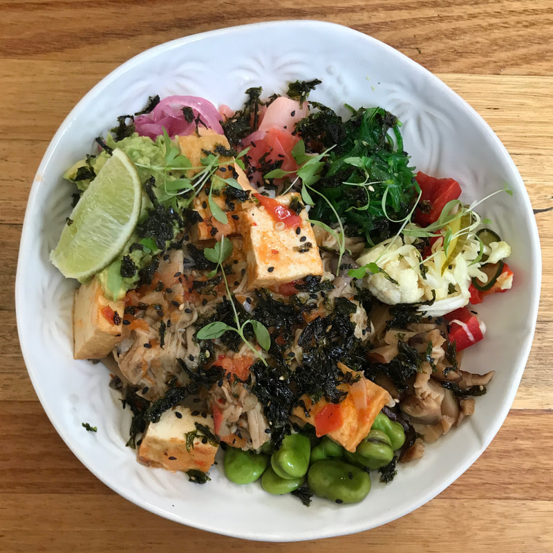 White bowl with colourful veggies, tofu, herbs and condiments
