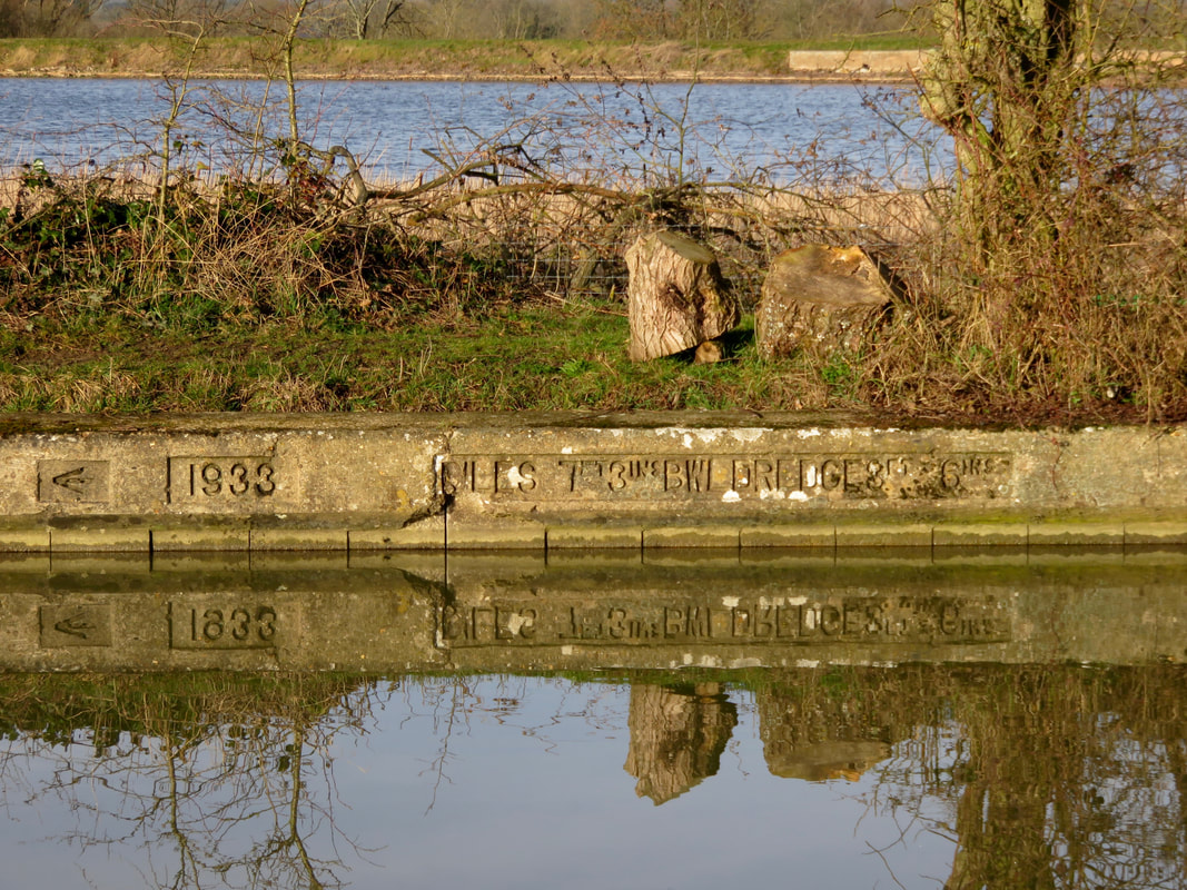 Concrete canal border with writing stamped into it, reflections and water