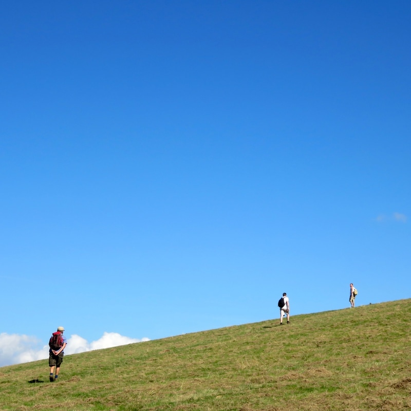 people, hill and bright blue sky