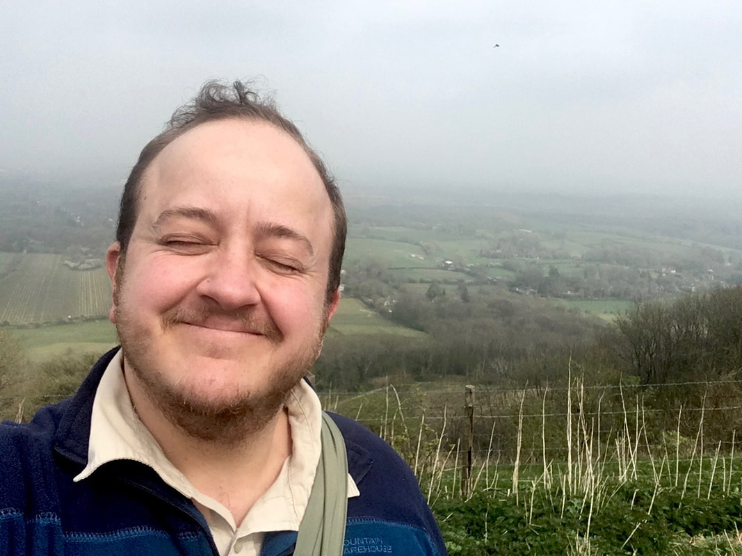 Selfie of person smiling with eyes closed and landscape behind
