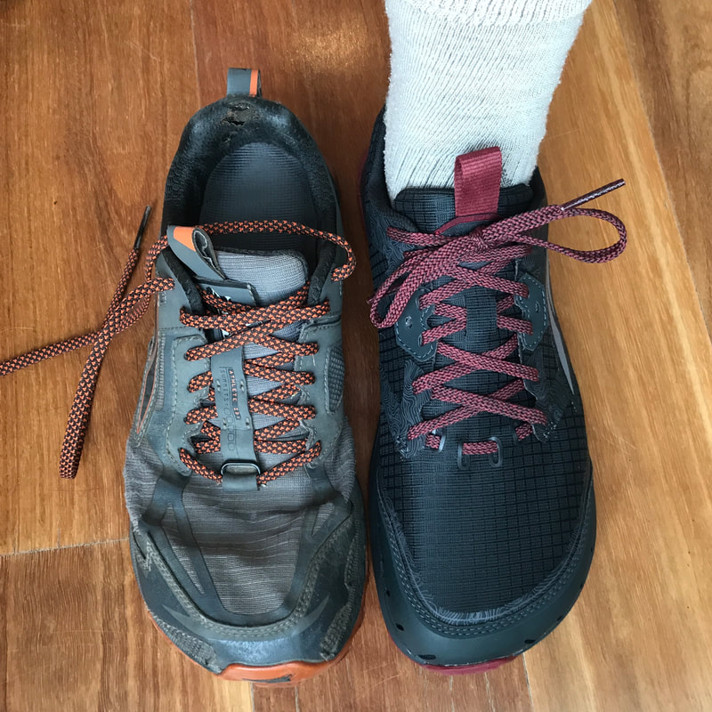 Showing two shoes, side by side - one grey and orange, the other black and dark red.