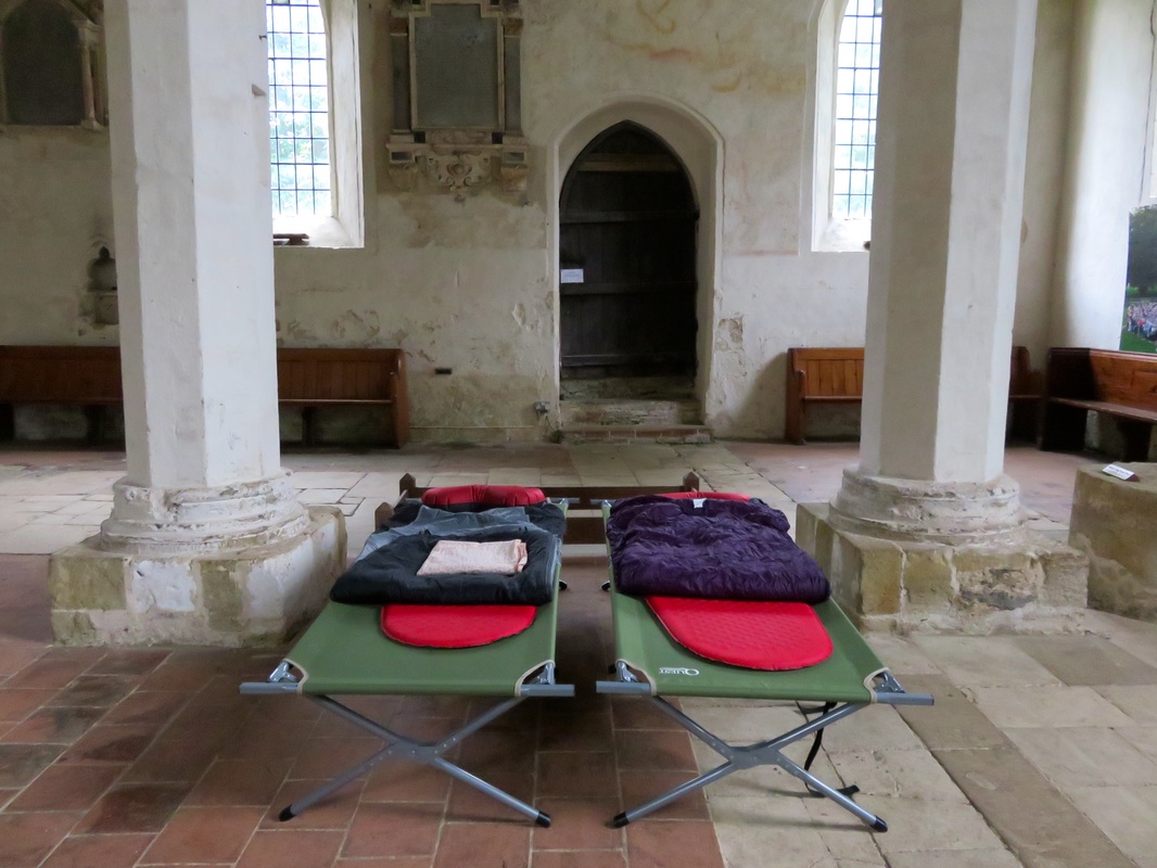 Two camp beds with sleeping gear in a large church