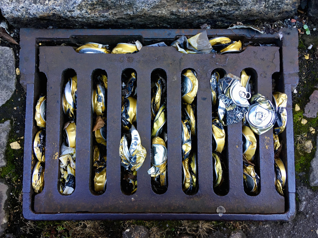 Gold cider cans stuffed into a metal grate