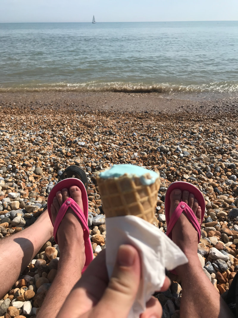 icecream cone, feet in thongs and sea with a faint sailboat on it