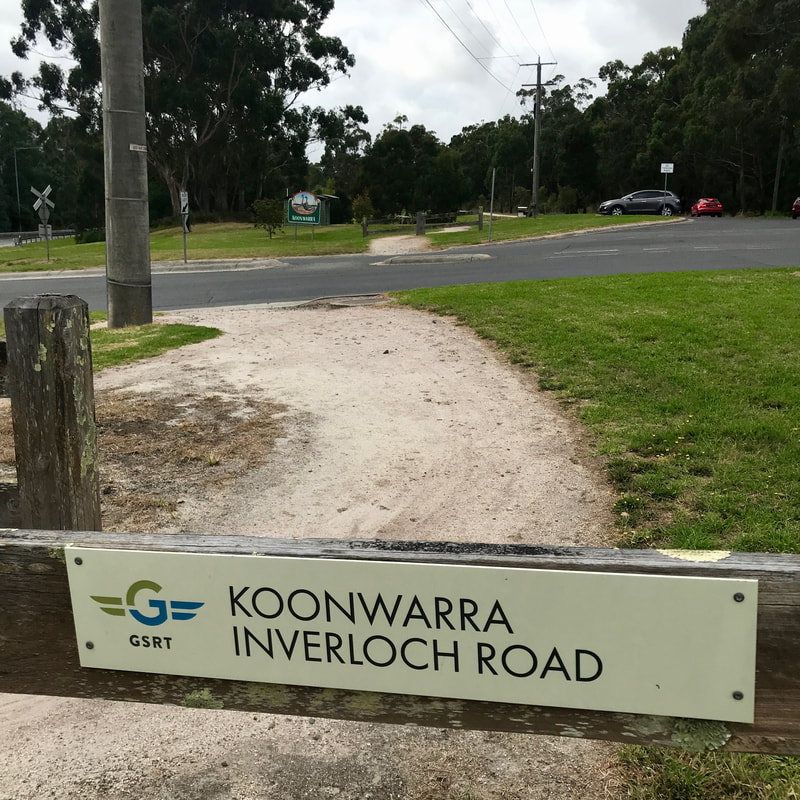 Gravel trail with sign on a barrier saying KOONWARRA INVERLOCH ROAD