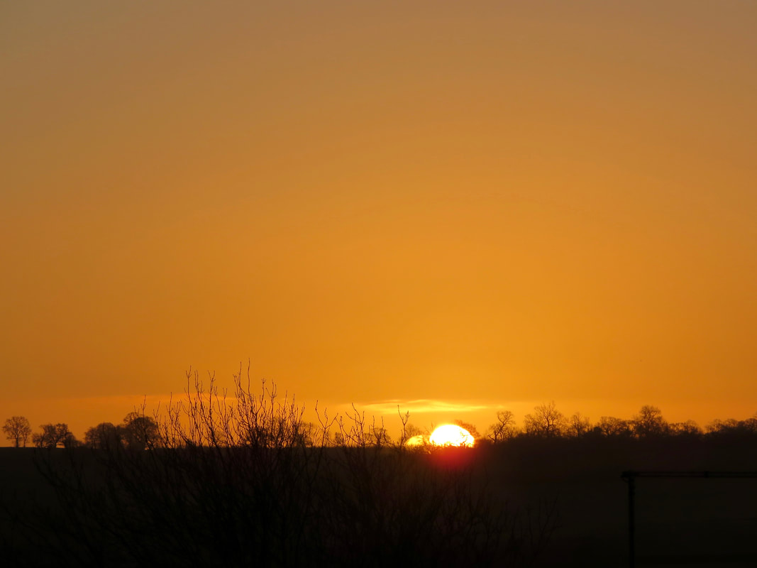 Sun rising over silhouetted hilltop into an orange sky