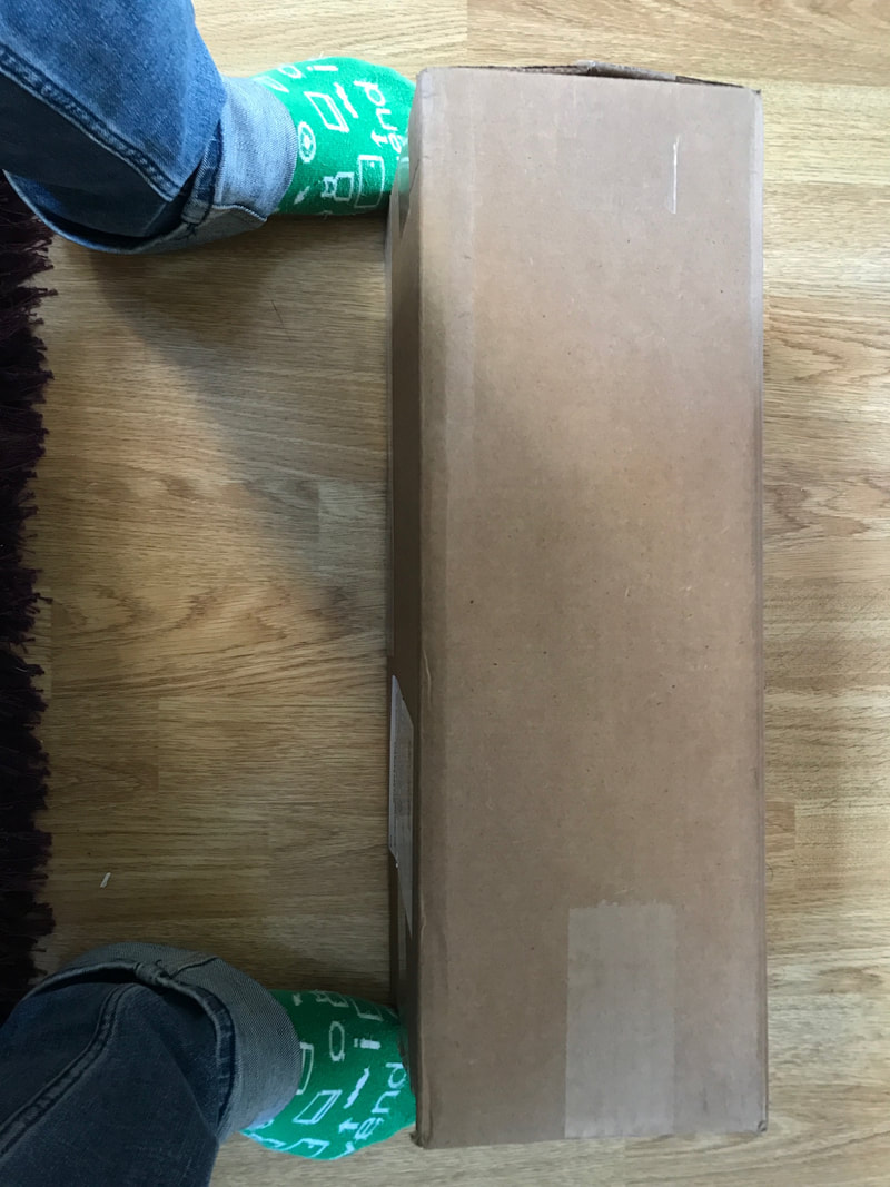 Looking down at a box, framed by feet in green socks