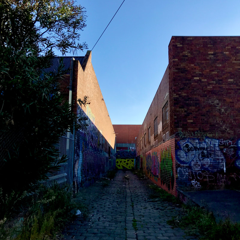 looking up a short alleyway with graffiti on the brick walls