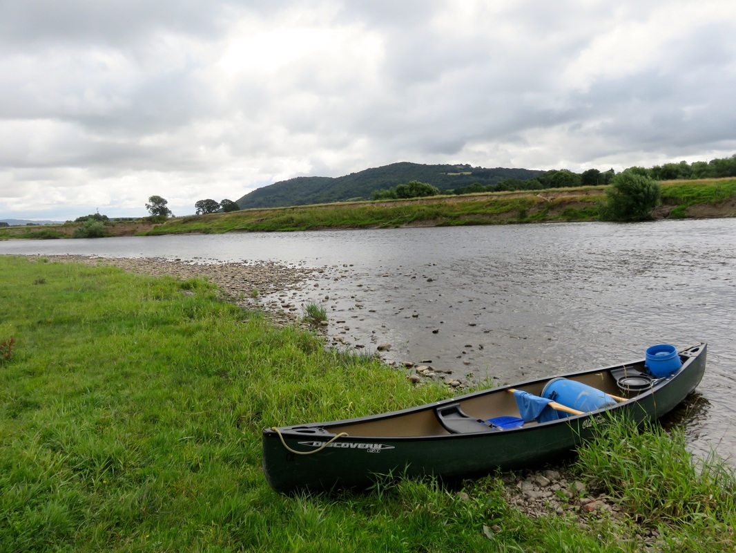 River and canoe, hill in background