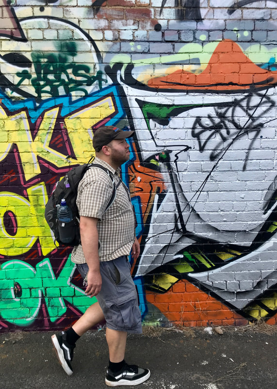 Person walking in front of brightly coloured graffiti