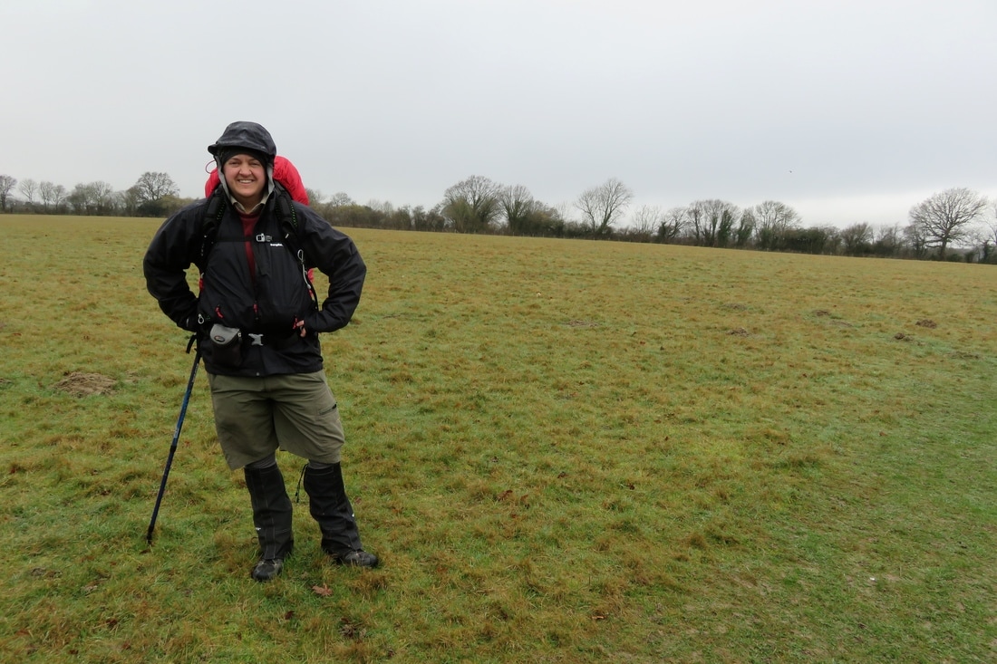 person in field in gaiters and raincoat