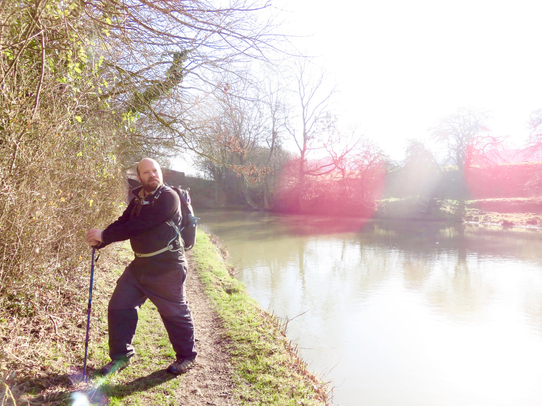 Person posing with a walking stick beside the canal