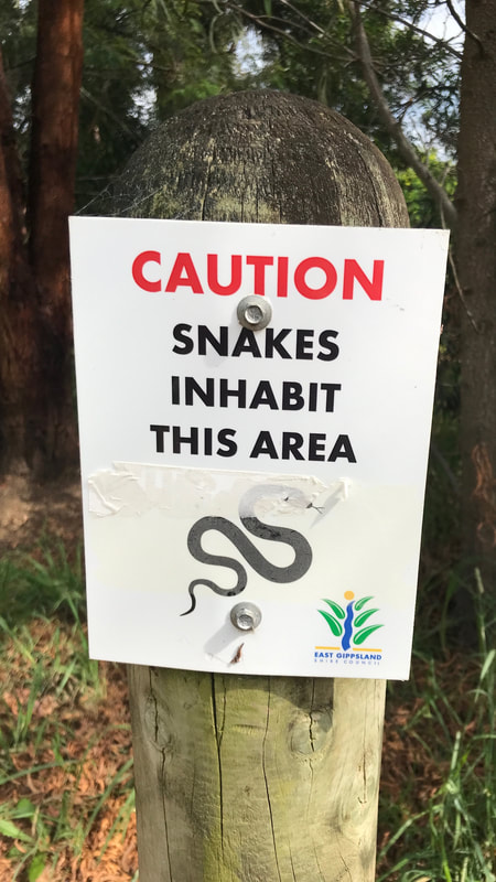 Sign saying CAUTION snakes inhabit this area