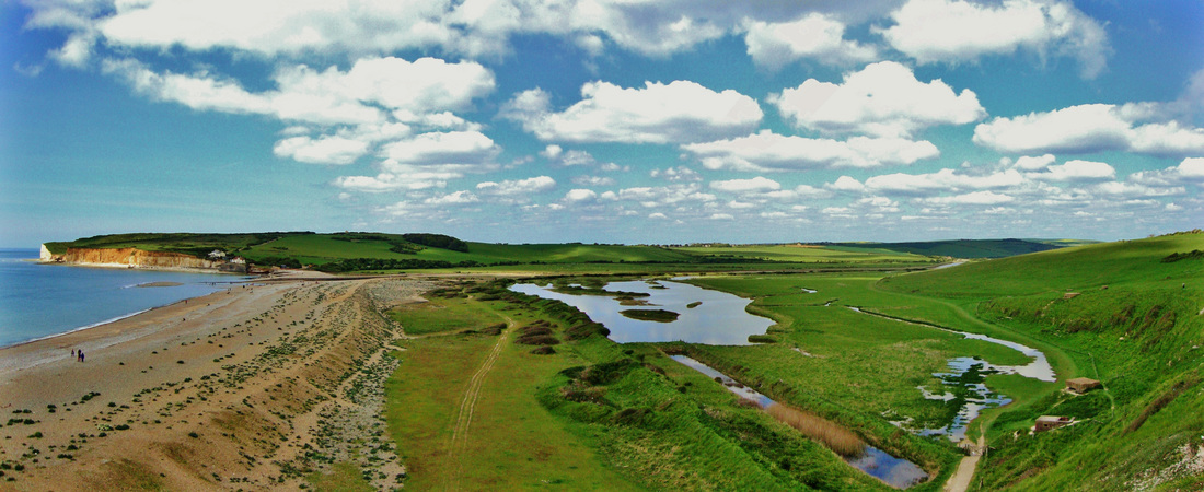 Panorama in saturated colours of a green valley with river leading to a beach