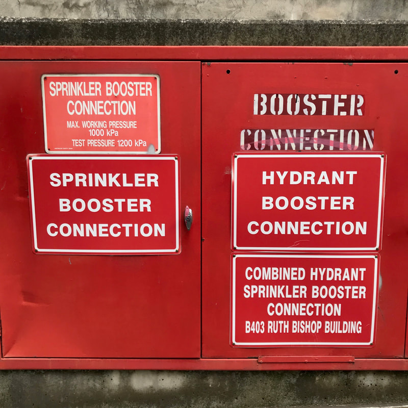 Red box with multiple signs indicating it contains BOOSTER CONNECTION or SPRINKLER BOOSTER CONNECTION or HYDRANT BOOSTER CONNECTION or COMBINED HYDRANT SPRINKLER BOOSTER CONNECTION