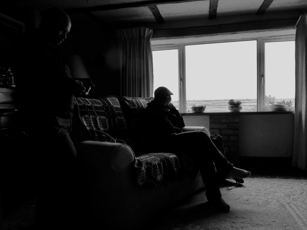Black and white photo of person on couch looking out of window