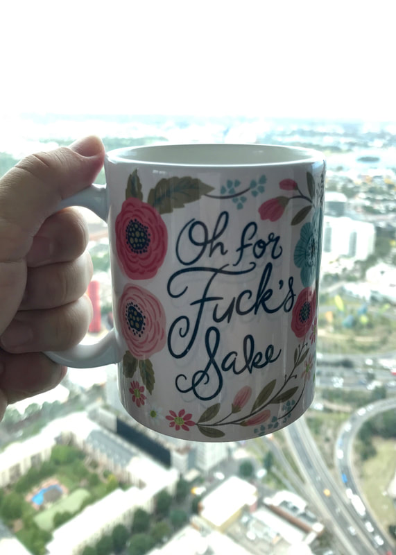 Cup with flowers and cursive writing saying Oh for Fuck's Sake