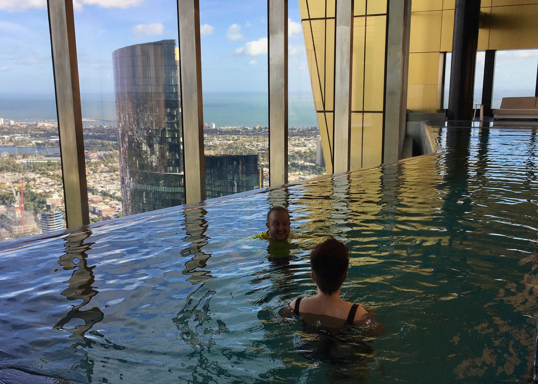 Two people in a pool with the same view out of the full length windows