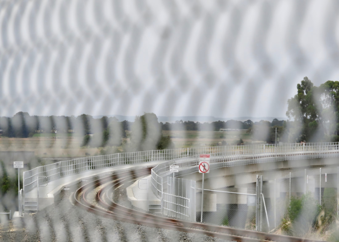 Pattern of out of focus wire fencing overlaid on a curved rail bridge