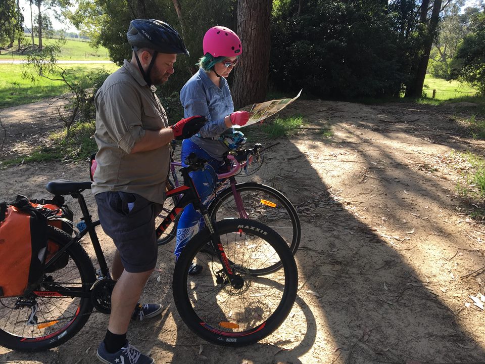 Two people on bikes looking at phone and map