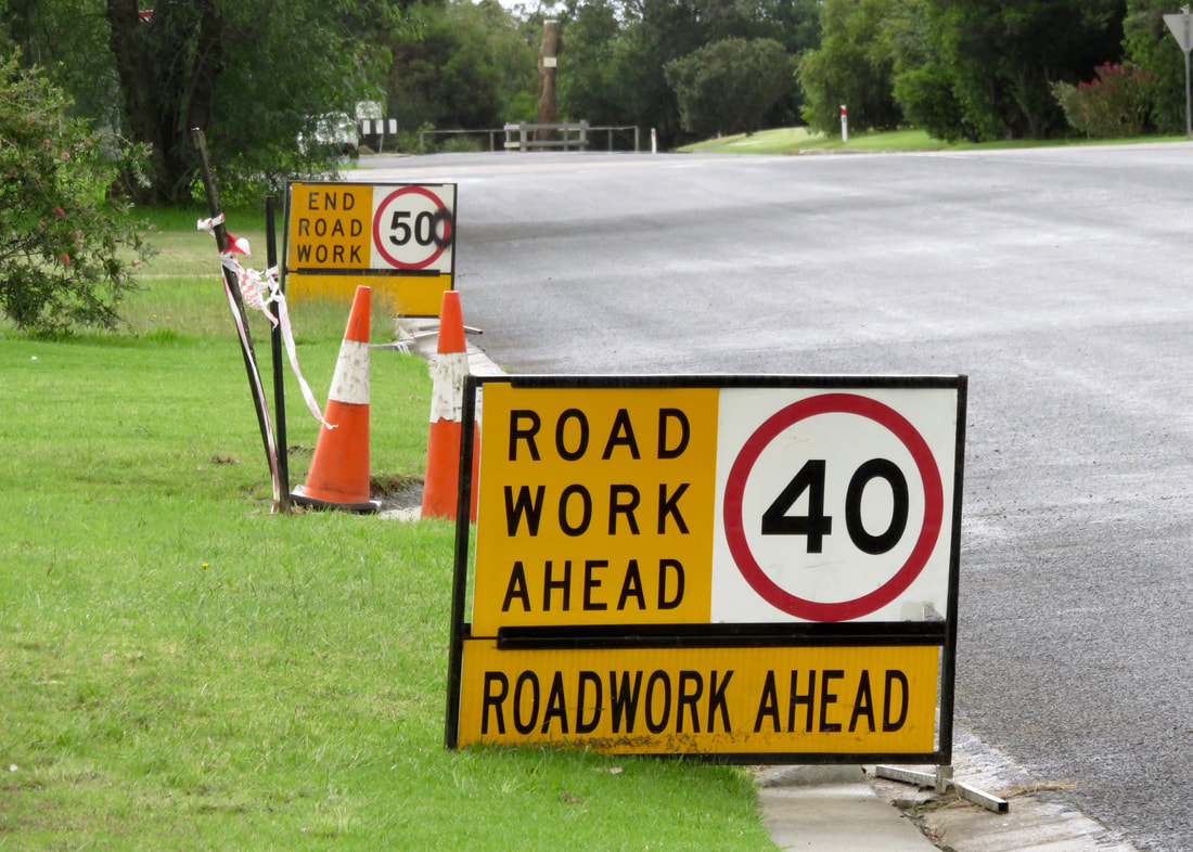 one sign saying ROAD WORK AHEAD 40 and another a few metres away saying END ROAD WORK 50 (someone has sprayed an extra 0 onto 50)