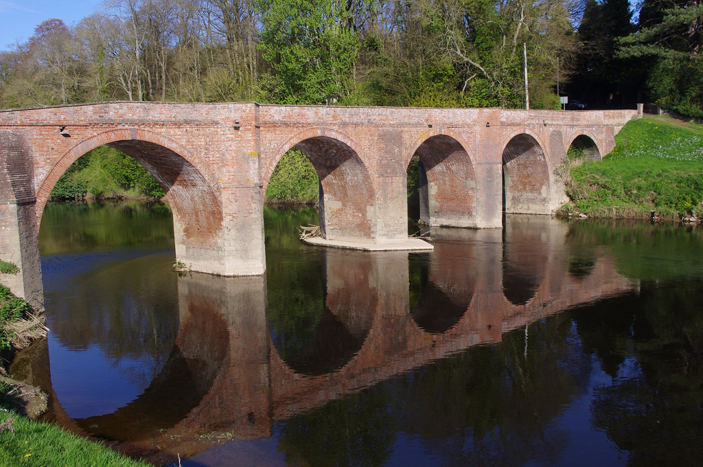 Red brick bridge with arches over river