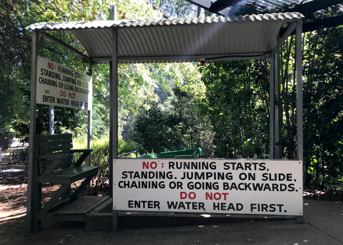 Sign reading NO: RUNNING STARTS, STANDING, JUMPING ON SLIDE, CHAINING OR GOING BACKWARDS. DO NOT ENTER WATER HEAD FIRST.