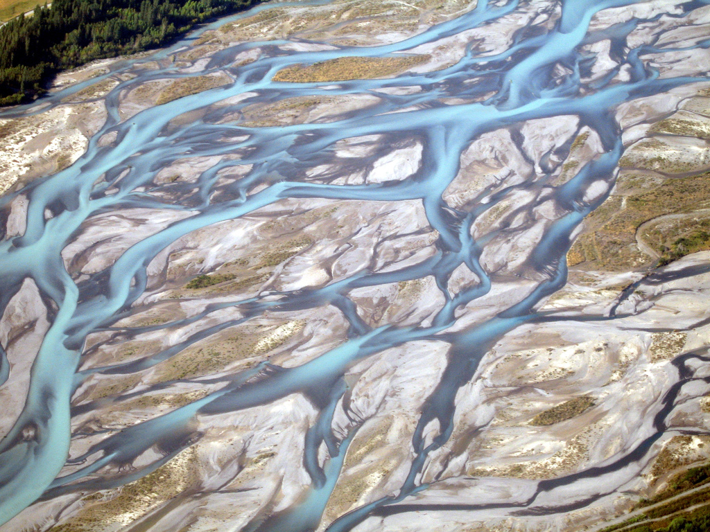 Aerial shot of wide river bed with ribbons of pale blue river