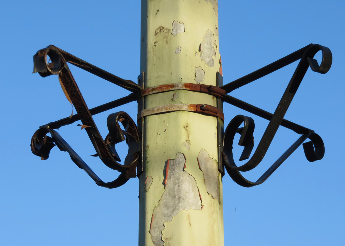 lamp post and metal bracket against blue sky