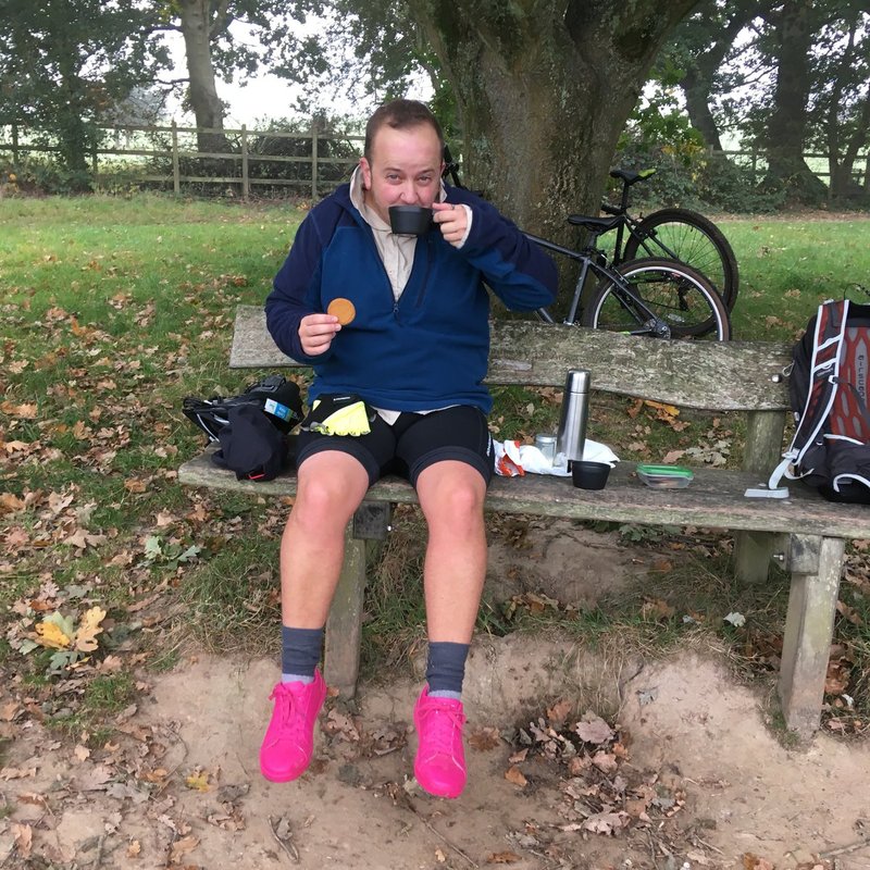 Person in pink shoes sitting on bench sipping tea