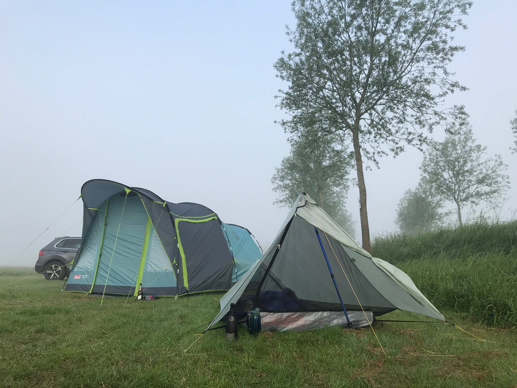 Two tents in a misty field with trees to the side