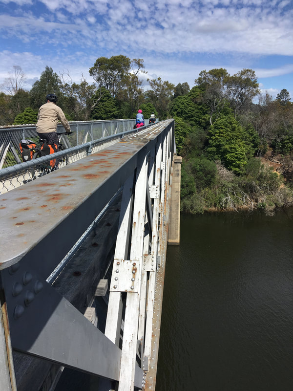 Cyclists crossing metal bridge above river