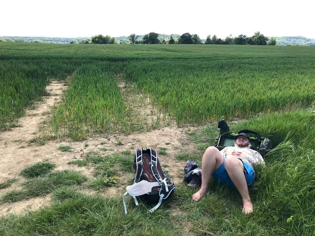 person lying down at the edge of a wheat field