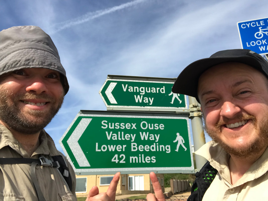 selfie of two smiling people pointing to a sign