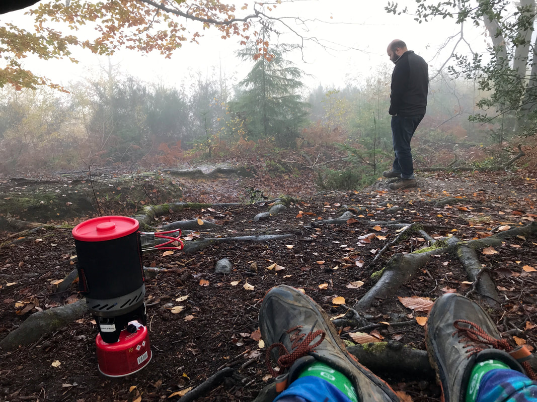 Person stands in a misty, autumnal wood - feet and gas stove in the foreground
