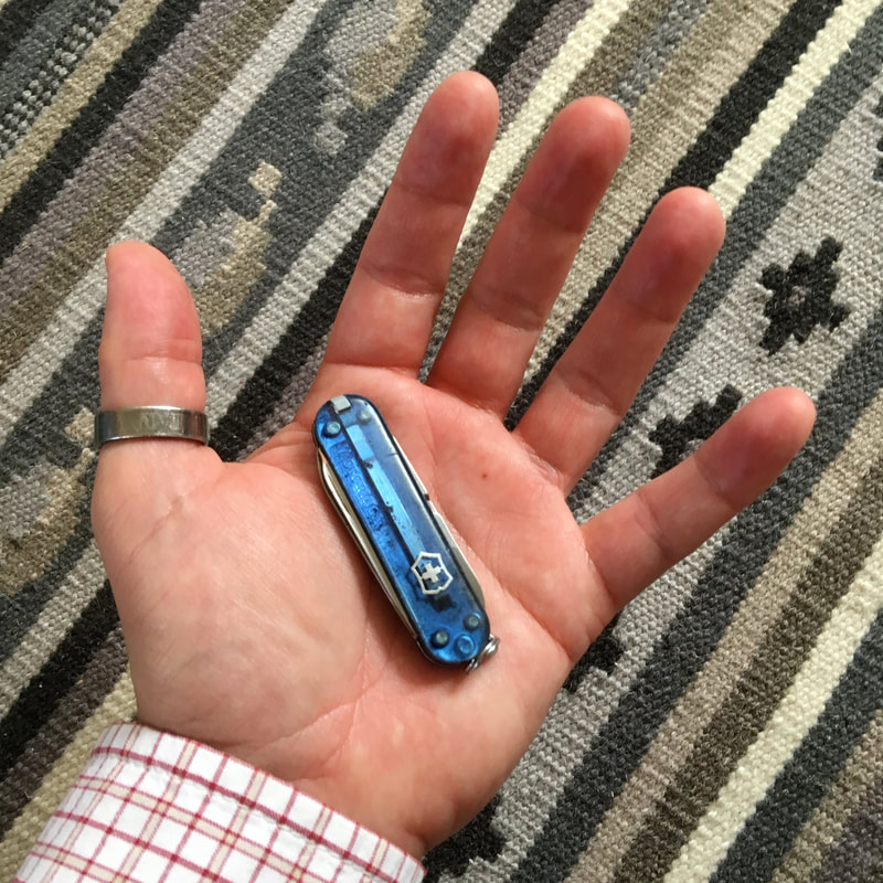 Small blue pocket knife in palm of hand
