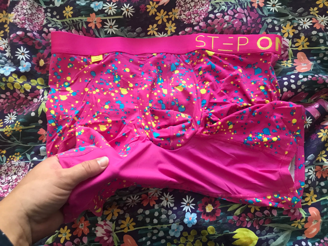 Bright pink undies with blue and yellow spots, a hand holds up the gusset to show a panel of slippy pink material