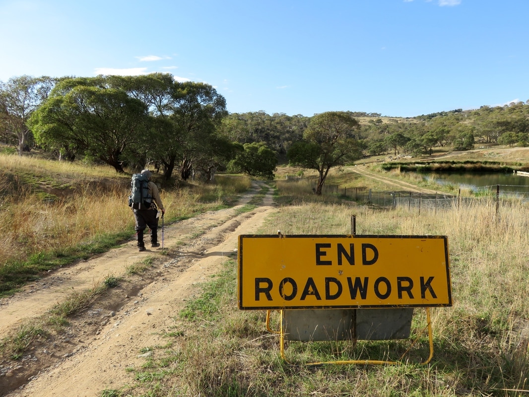 Person walking on road and 'end roadwork' sign